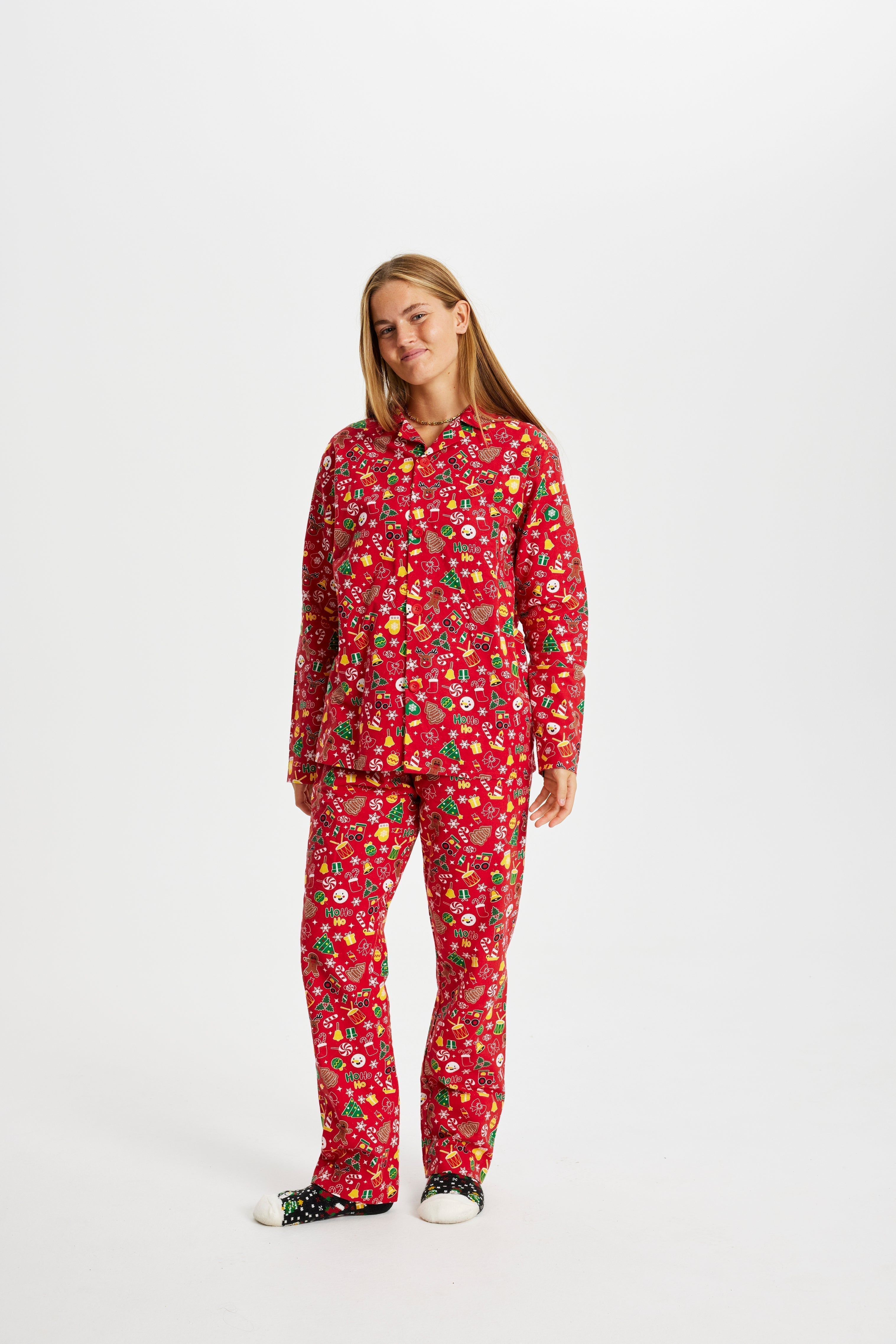 Une femme, les mains dans les poches, portant un pyjama rouge à imprimé de Noël.